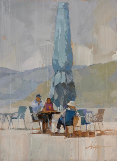 Trois touristes assis en terrasse à proximité d'un parasol fermé, face à la montagne.